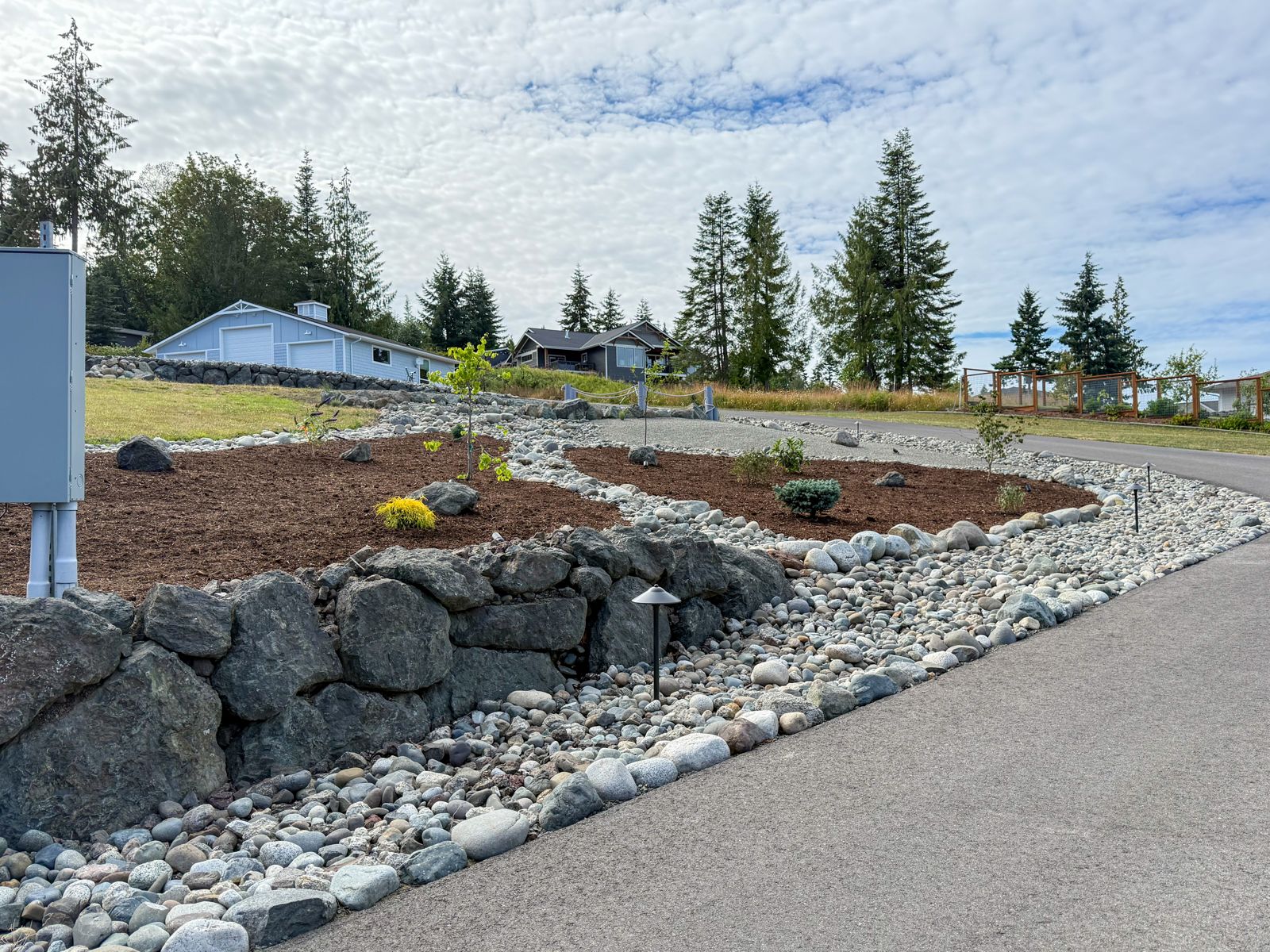 Boulder wall, river rock and new planting beds with path lights along a driveway