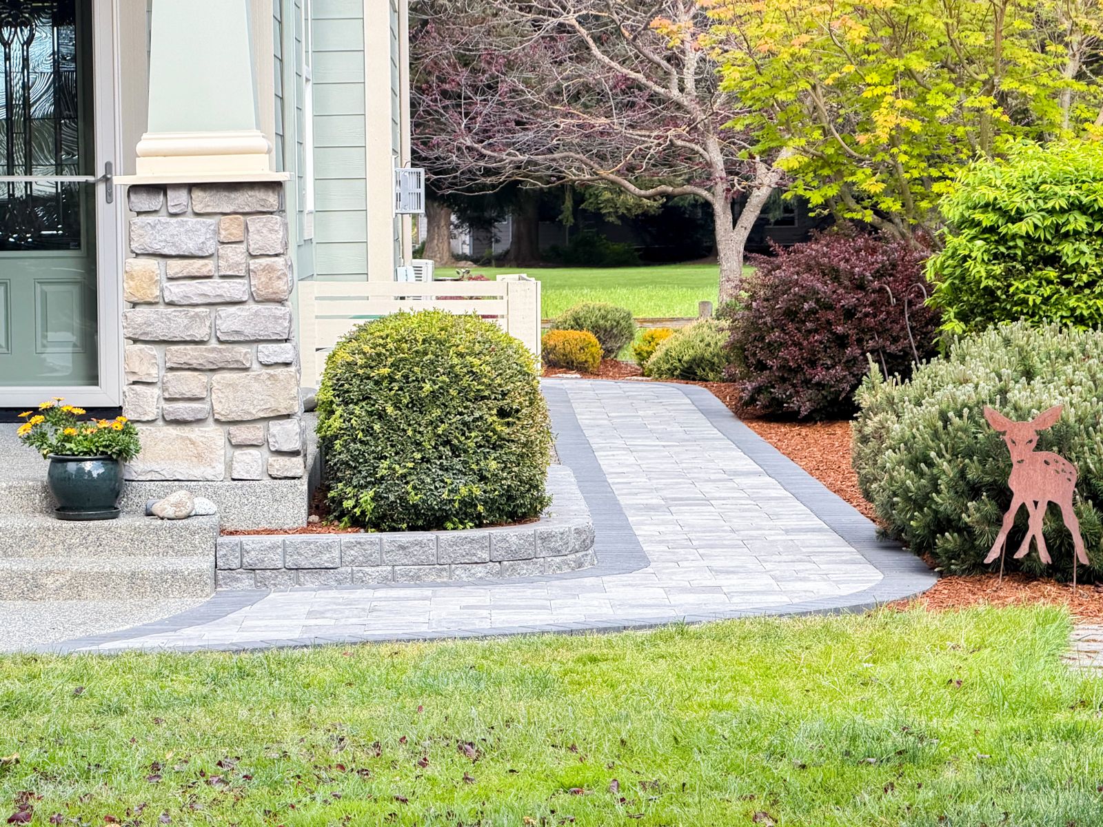 Light gray paver front walkway with a charcoal border and a block planter