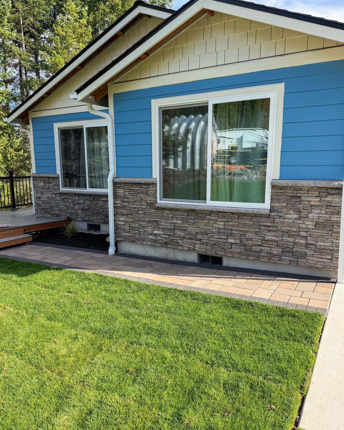 Paver walkway along a blue house with stone veneer and new lawn