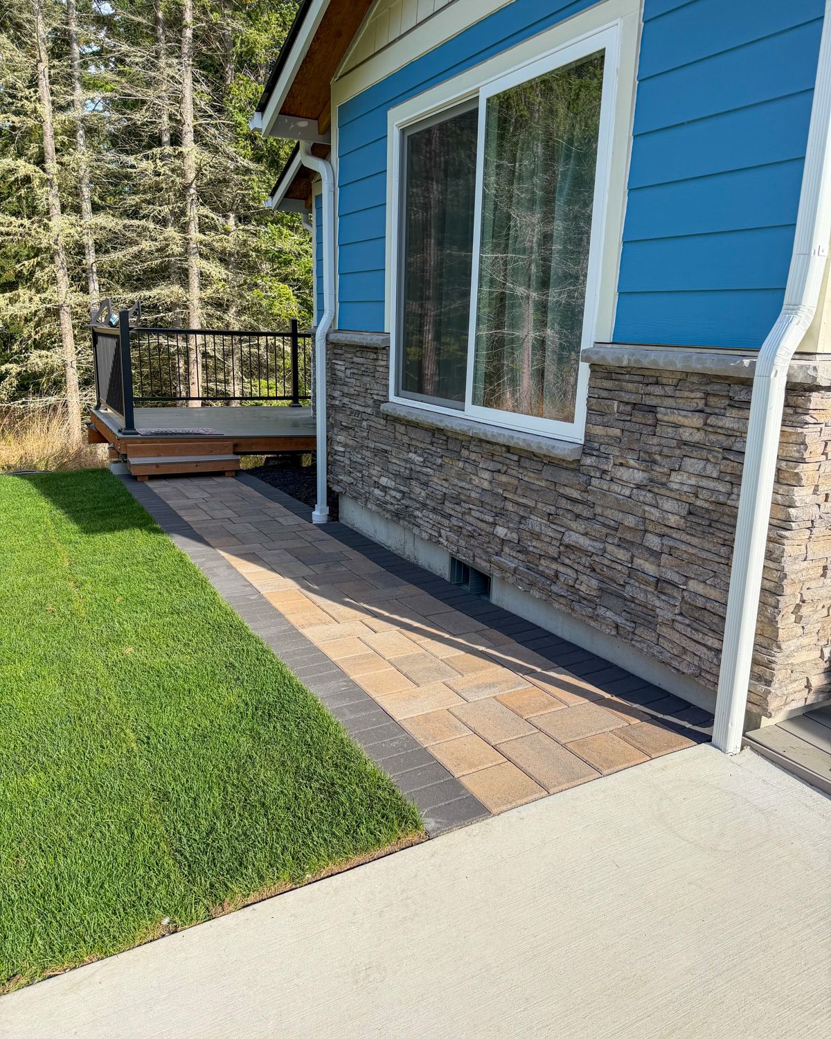 Paver walkway leading to a back deck alongside new lawn